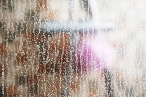 Blurred shower cabin and faucet and detailed view of limescale on the glass. Housekeeping and cleaning concept