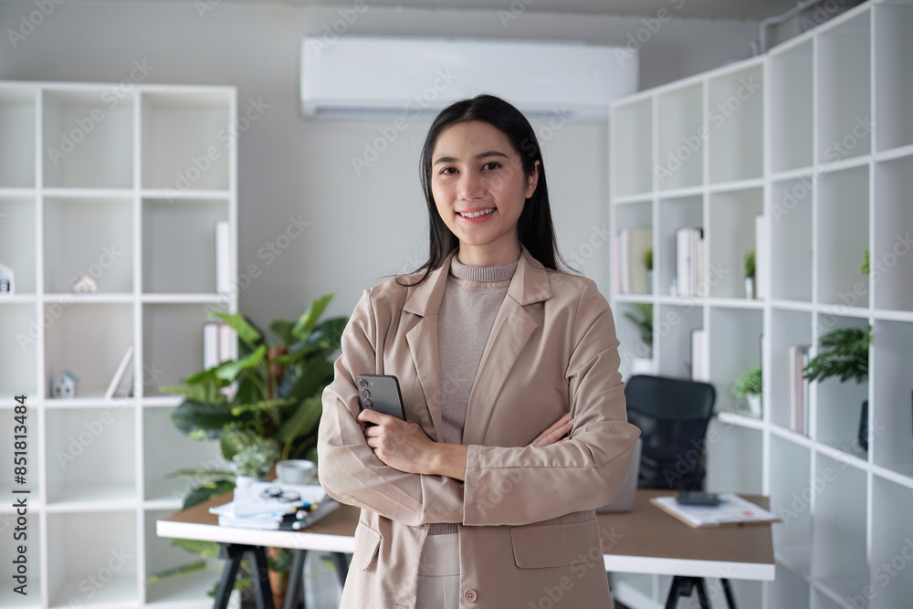 Confident businesswoman holding smartphone in modern office. Concept of leadership, technology, and business Confident businesswoman holding smartphone in modern office. Concept of leadership, technology, and business