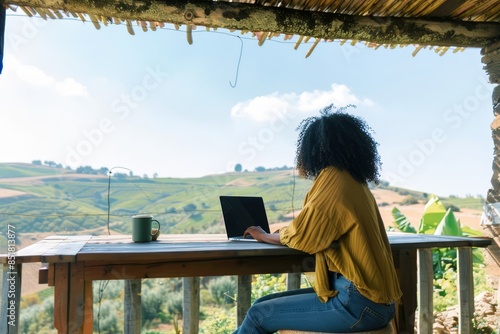 A woman working on a laptop while enjoying a scenic countryside view, epitomizing the perfect blend of work and relaxation in nature.