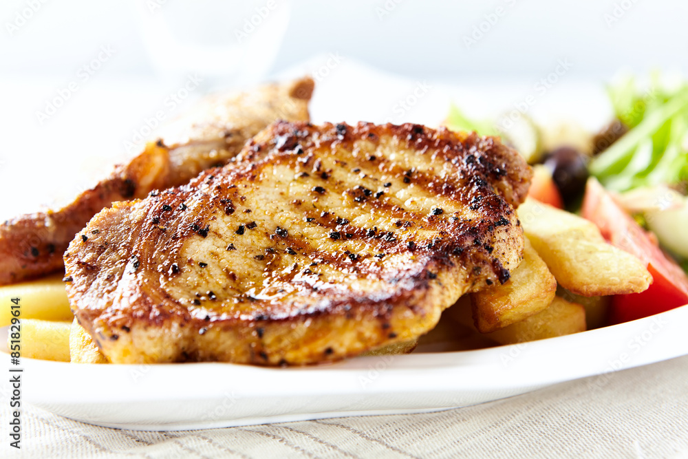 Grilled Steaks with french fries and fresh salad. Bright wooden background. Grilled Steaks with french fries and fresh salad. Bright wooden background.