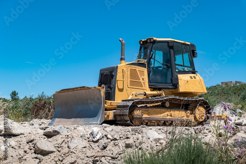 Wallpaper Mural Bulldozer de esteiras a operar num terreno rochoso sob um céu azul Torontodigital.ca