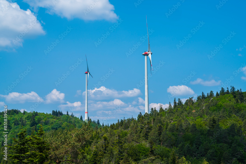 Germany, Two giant wind turbines in green woodland of black forest schwarzwald nature landscape generating electricity