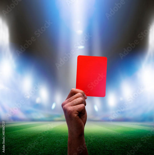 Hand mit roter Karte in einer Fussballarena im Scheinwerferlicht