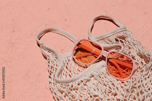 Market mesh tote styled on a textured coral background with orange-colored sunglasses in sunlight