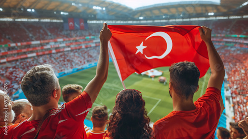 Turkish football soccer fans in a stadium supporting the national team wearing red shirt, supporting , cheering and rising Turkish national flag in european football league photo