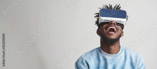 A man wearing VR glasses laughing while standing against white background