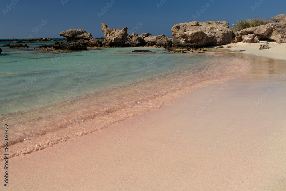 Sandy beach background. Gentle waves crash upon the shore. Pink sand. Pink shells. Elafonisi. Crete. Greece. Sandy beach background. Gentle waves crash upon the shore. Pink sand. Pink shells. Elafonisi. Crete. Greece.