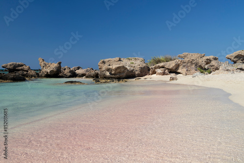 Sandy beach background. Gentle waves crash upon the shore. Pink sand. Pink shells. Elafonisi. Crete. Greece.