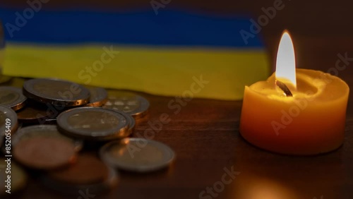 A lamp among coins and a burning candle. Rising electricity prices and blackout in Ukraine due to war