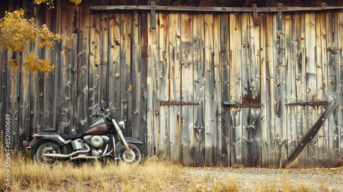 Motorcycle parked against worn wooden barn wall photo