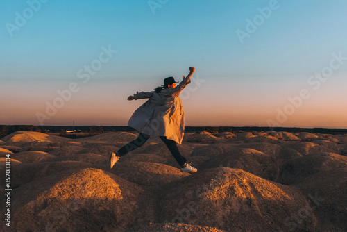 A happy woman jumping against the background of an unusual landscape at a quarry. The concept of freedom, enjoyment