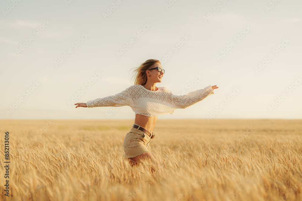 Carefree young woman with arms outstretched in a wheat field at sunset, embodying freedom, joy, and nature's beauty. Carefree young woman with arms outstretched in a wheat field at sunset, embodying freedom, joy, and nature's beauty.