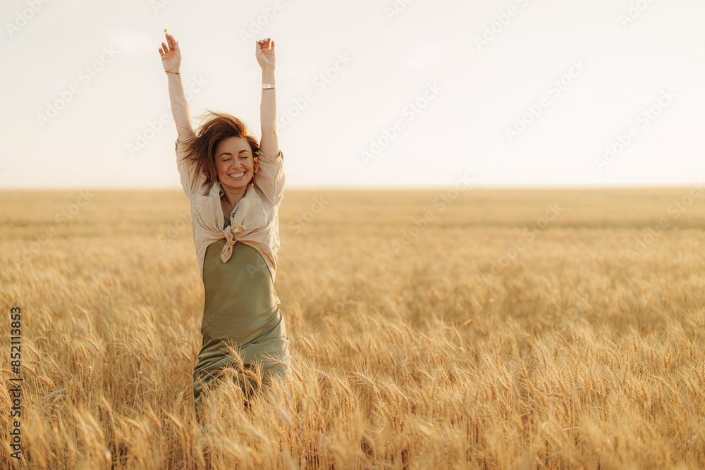 Happy woman with arms raised celebrating freedom and life in a beautiful golden wheat field at sunset, feeling positive and cheerful. Happy woman with arms raised celebrating freedom and life in a beautiful golden wheat field at sunset, feeling positive and cheerful.