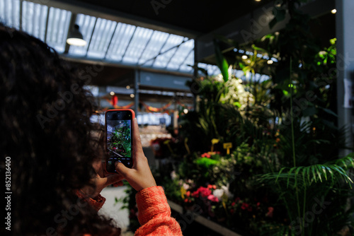 Young woman taking a photo with a mobile phone of some plants