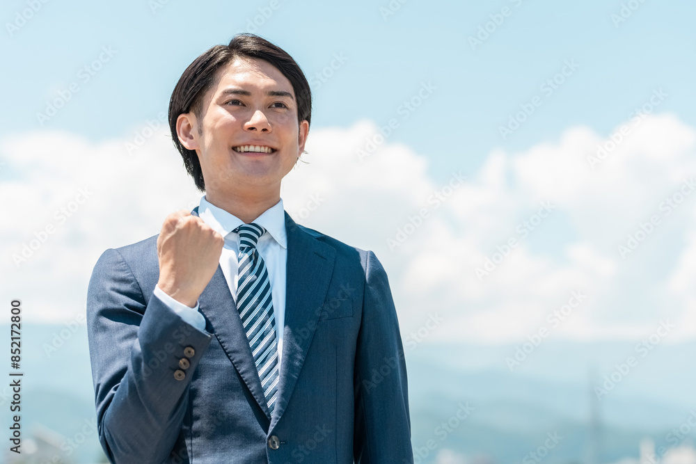 青空の下でガッツポーズするアジア人ビジネスマン（弁護士,税理士,会計士,行政書士,銀行員,公務員）
