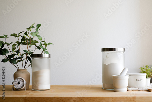 Minimalist still life kitchen counter top with baking ingredient and utensil on a wooden surface. Aesthetic appeal related to interior design and cooking background with copy space.