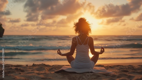 Young woman practicing yoga on sand at beach during sunset