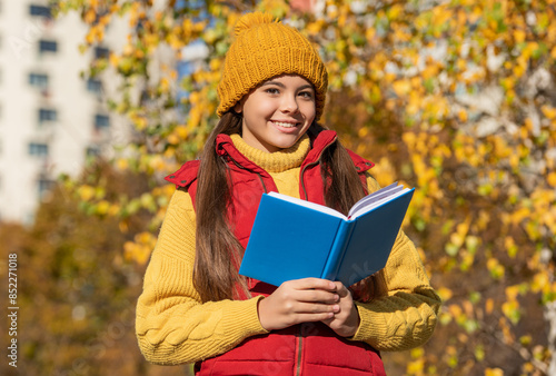 smiling teen girl read school book in autumn