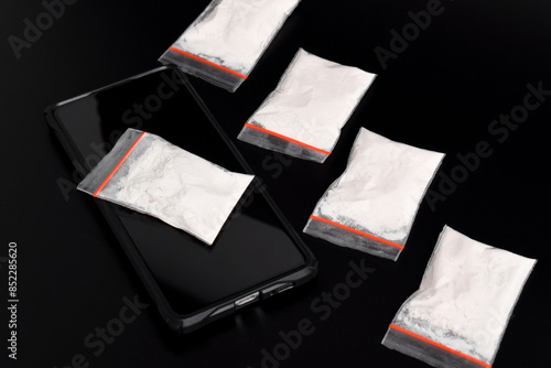 Cocaine in a plastic package on a smartphone isolated on a black background. Illustration of illegal drug substances, narcotics