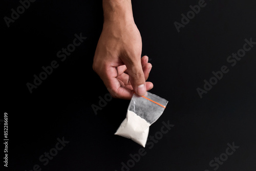 Hand holding Cocaine in plastic packet isolated on black background. illustration of illegal drug substances, narcotics photo