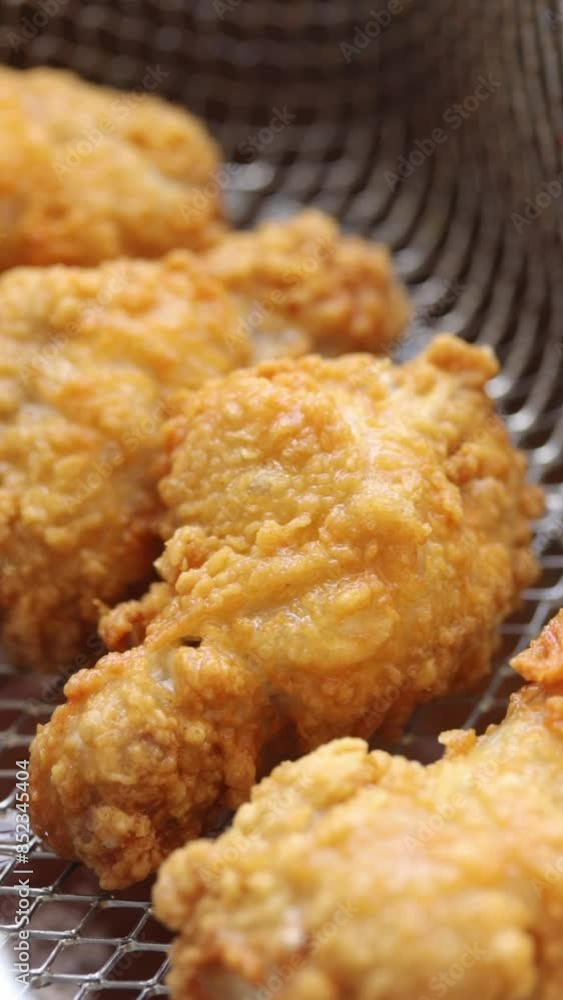 Deep-fried Crispy Chicken Drumsticks in Deep Fryer Basket and Lift Them Out of The Boiling Oil. Close-up Shot Deep-fried Crispy Chicken Drumsticks in Deep Fryer Basket and Lift Them Out of The Boiling Oil. Close-up Shot