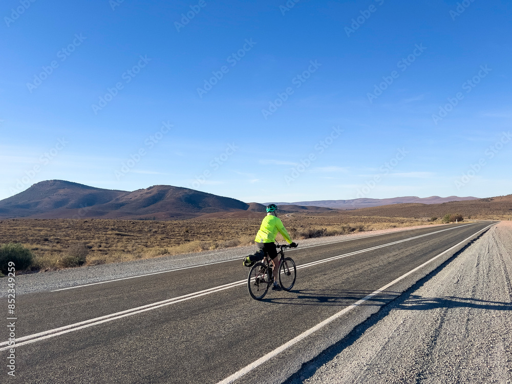 Cyclist on Remote Outback Road with Mountains Cyclist on Remote Outback Road with Mountains