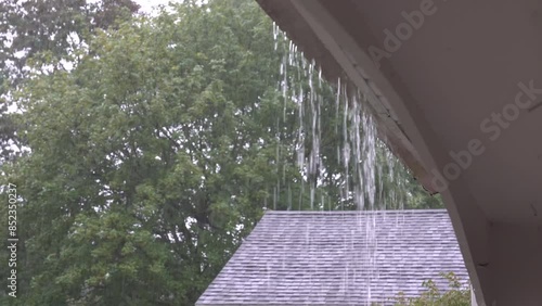 Rain pouring down on house overflowing gutters