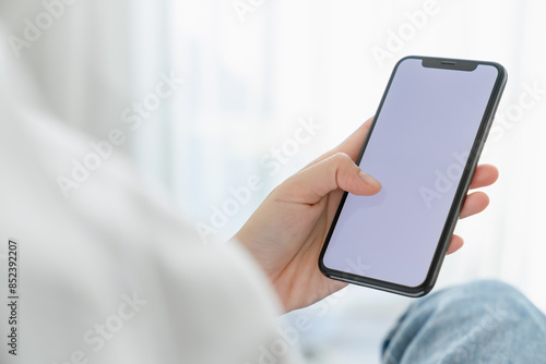 Hand holding smartphone mockup of blank screen for graphic display montage.