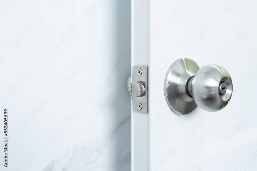 Detailed view of a stainless steel door knob on a white door showcasing modern and minimalist design Detailed view of a stainless steel door knob on a white door showcasing modern and minimalist design