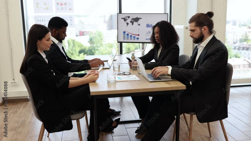 Diverse team of professionals engaged in business meeting discussing data reports and charts in modern office setting. Group includes men and women working collaboratively on laptops and documents. Diverse team of professionals engaged in business meeting discussing data reports and charts in modern office setting. Group includes men and women working collaboratively on laptops and documents.
