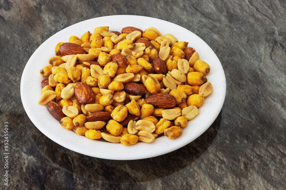 Roasted peanuts, corn and almonds in a plate on the table Roasted peanuts, corn and almonds in a plate on the table