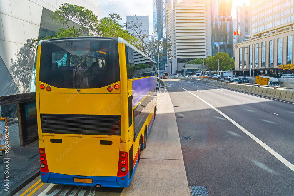 Fototapeta premium Double-decker city shuttle bus at an stopped at the stop to drop off and pick up passengers rides down the street, aerial view