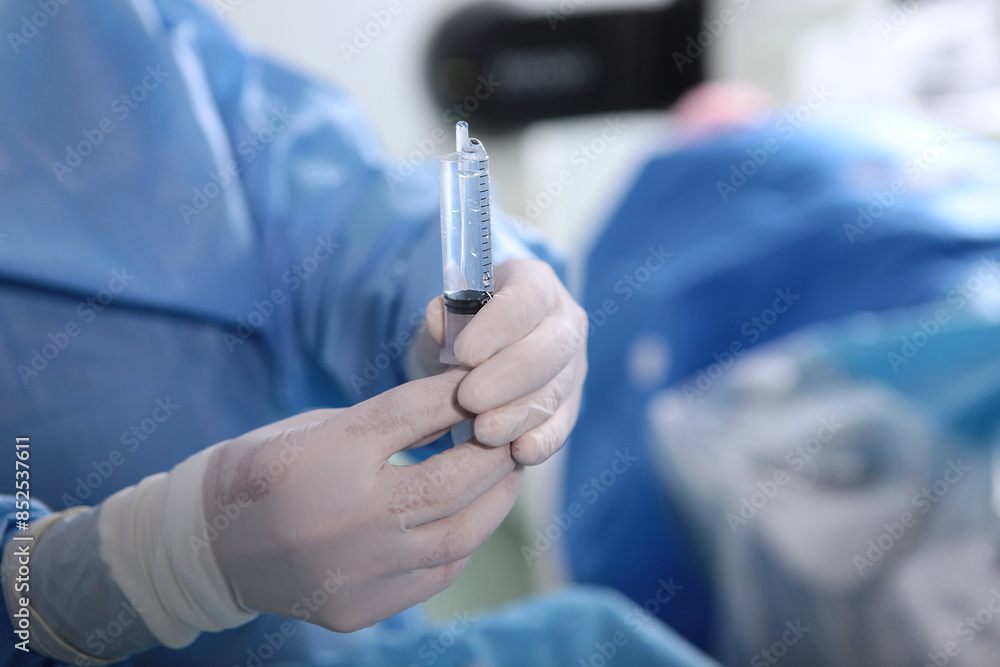 An injection syringe in the hands of a surgical assistant. Surgical interventions on blood vessels. Endovascular surgery. Removal of blood clots. An injection syringe in the hands of a surgical assistant. Surgical interventions on blood vessels. Endovascular surgery. Removal of blood clots.