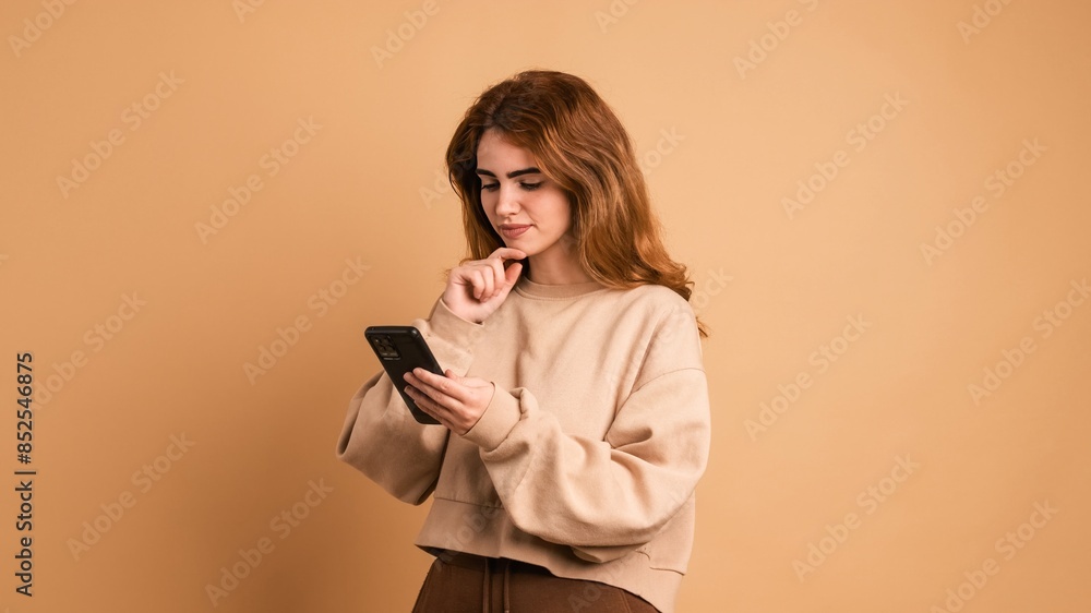 Thoughtful young woman browsing mobile phone in studio Thoughtful young woman browsing mobile phone in studio