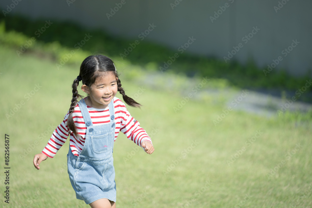 Smiling child (toddler) running on lawn Park, nursery school and kindergarten with copy space on the right Smiling child (toddler) running on lawn Park, nursery school and kindergarten with copy space on the right