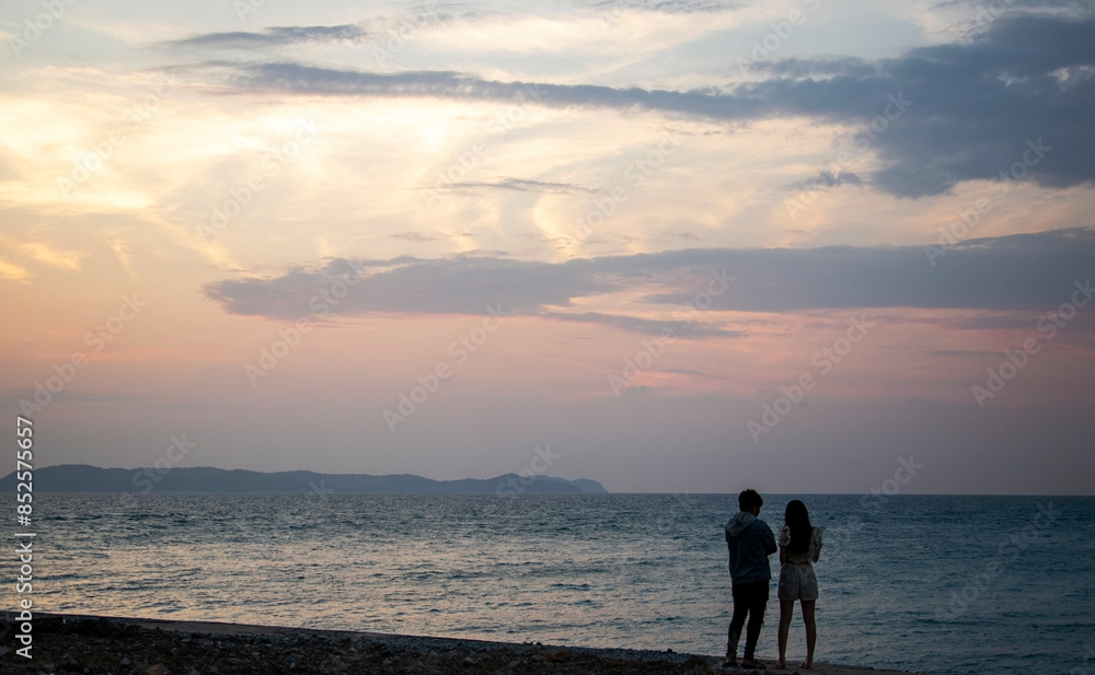 Fototapeta premium silhouette of a man and woman by the sea in the evening with a cloudy sky
