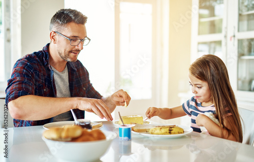 Breakfast, bread and daughter with dad, table or morning in kitchen, butter and dining in home. Healthy, father and food of family, child and man in house, eating and bonding with love together