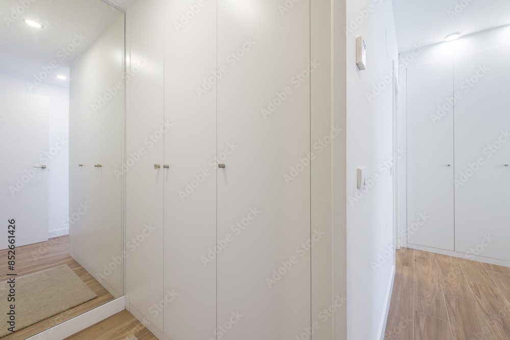 Modern white corridor with built-in wardrobes and wooden floor Modern white corridor with built-in wardrobes and wooden floor