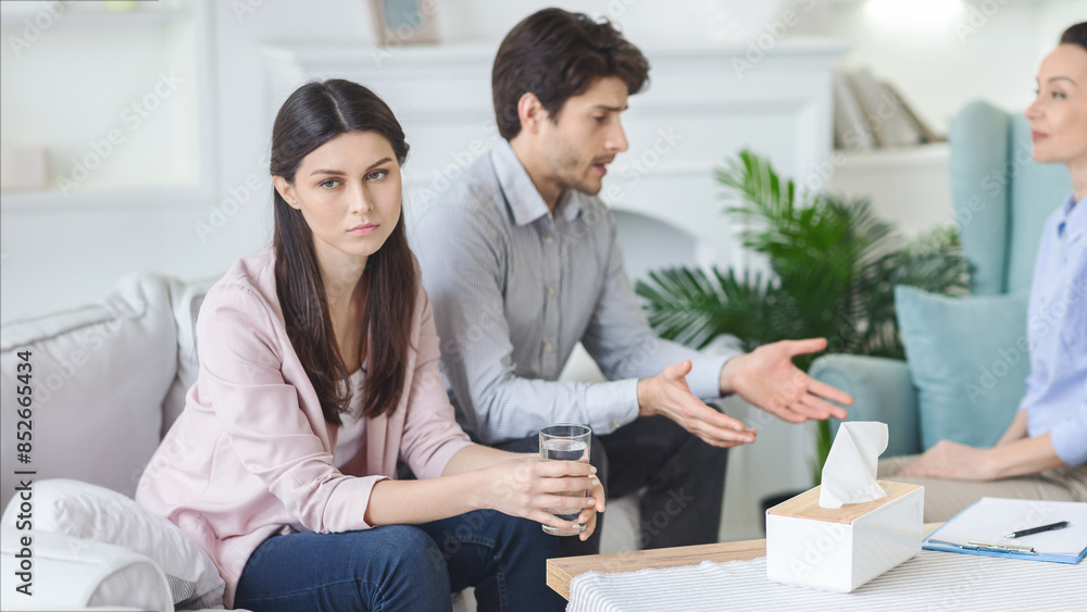 In a tranquil therapy setting, a young couple engages with a woman psychologist, working together to overcome personal hurdles and strengthen their relationship. In a tranquil therapy setting, a young couple engages with a woman psychologist, working together to overcome personal hurdles and strengthen their relationship.