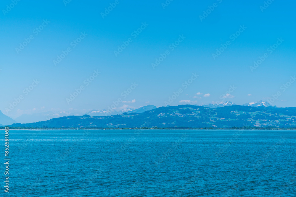 Germany, wonderful view to white snow covered mountain peaks of the alps and switzerland from lindau in summer with blue sky panorama