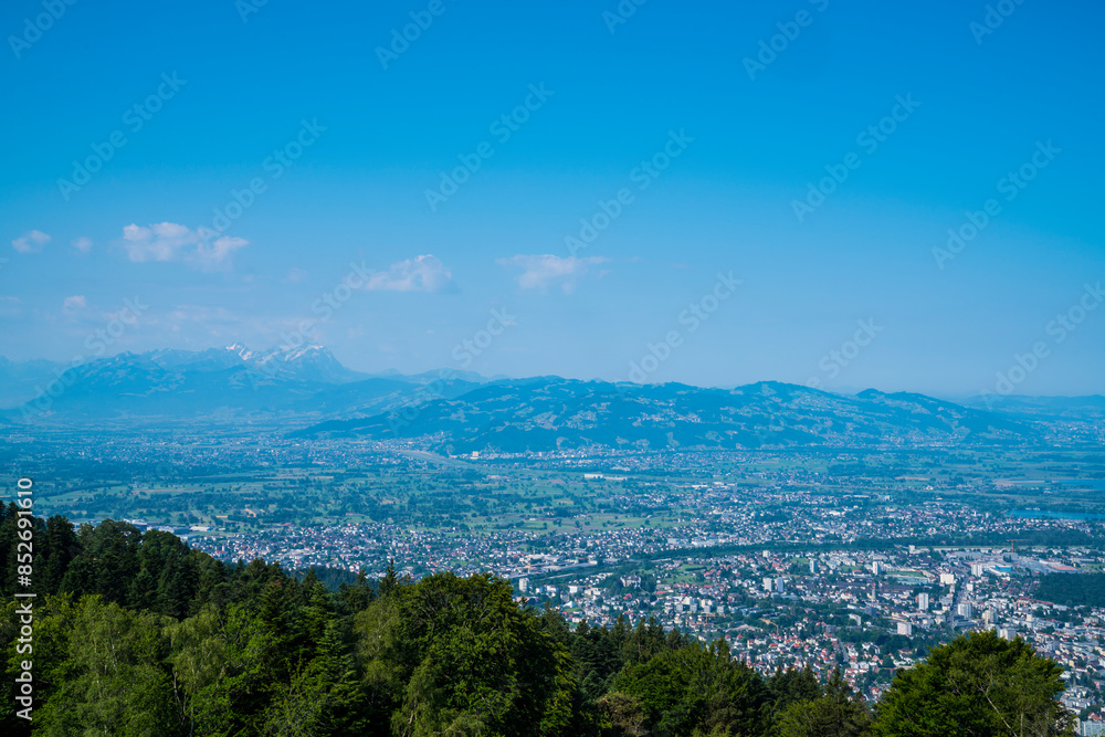 Austria, Panorama landscape mountain nature view from pfaender summit above tree tops wide view above alps, bregenz city houses to saentis peak with snow in summer