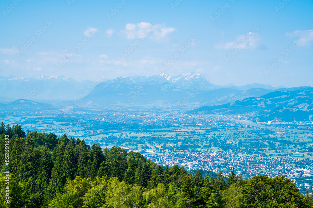 Austria, Panorama nature landscape mountain view from peak of pfaender above tree tops wide panoramic view above alps, bregenz city houses to saentis peak with snow