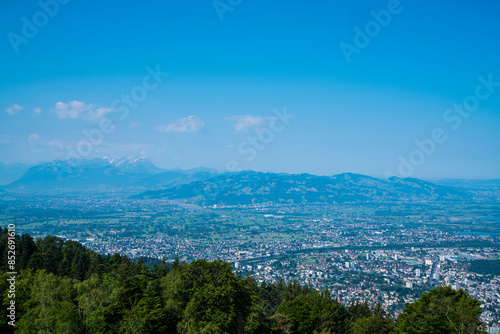 Obraz na płótnie Austria, Panorama landscape mountain nature view from pfaender summit above tree tops wide view above alps, bregenz city houses to saentis peak with snow in summer w salonie
