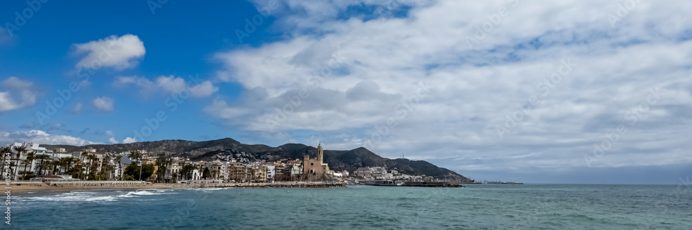 Fototapeta premium Quiet Mediterranean coastline with historic European architecture under a blue sky, ideal for travel and summer holiday themes