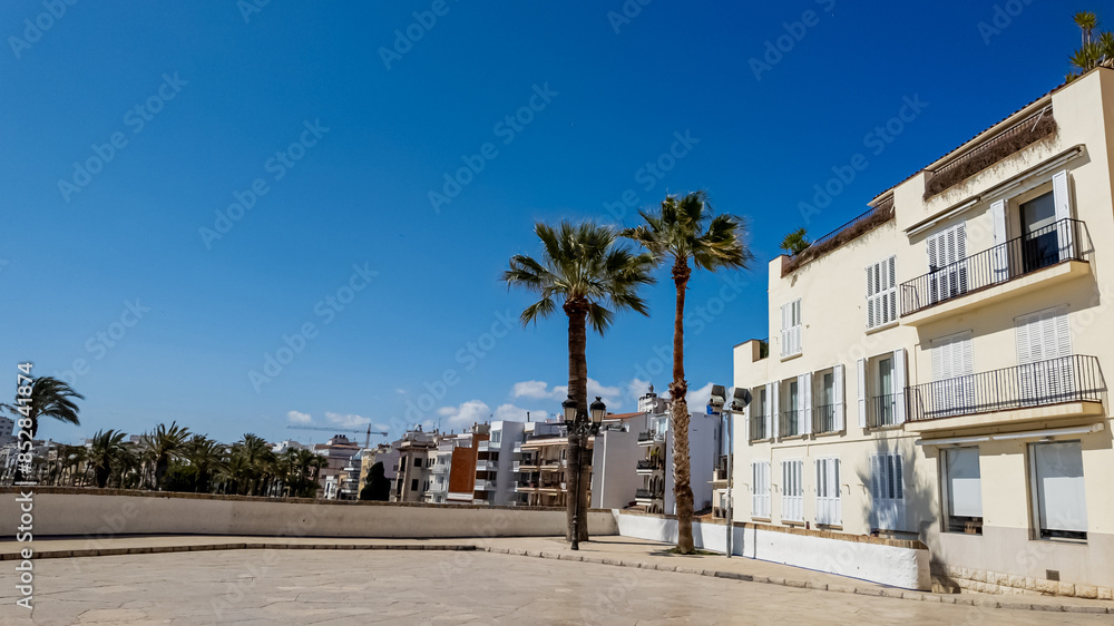 Fototapeta premium Sunny Mediterranean esplanade with white buildings and palm trees, evoking European summer holidays and Spanish coastal living