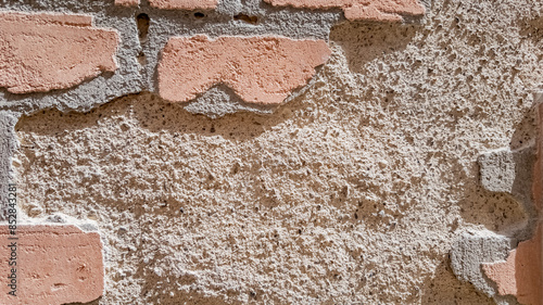 Close-up weathered brick wall texture with visible erosion for architectural backgrounds and renovation concepts, suitable for illustrating deterioration or historical preservation
