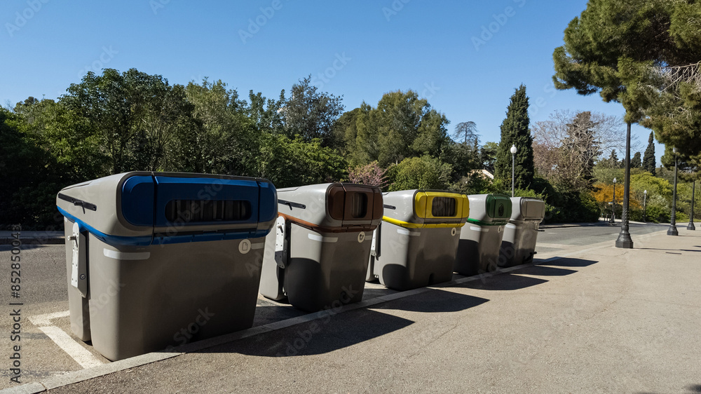 Row of various colored recycling bins in a park, symbolizing environmental conservation and waste management, related to Earth Day and sustainability initiatives Row of various colored recycling bins in a park, symbolizing environmental conservation and waste management, related to Earth Day and sustainability initiatives
