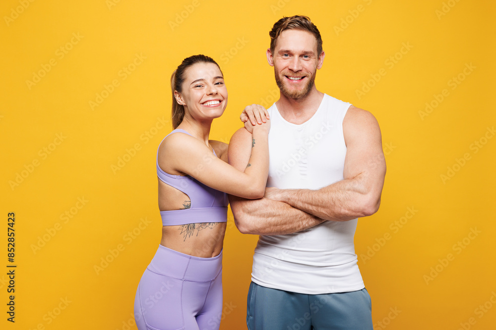 Young happy fitness trainer instructor sporty two man woman wears blue clothes spend time in home gym, wife put hand on husband shoulder isolated on plain yellow background. Workout sport fit concept. Young happy fitness trainer instructor sporty two man woman wears blue clothes spend time in home gym, wife put hand on husband shoulder isolated on plain yellow background. Workout sport fit concept.