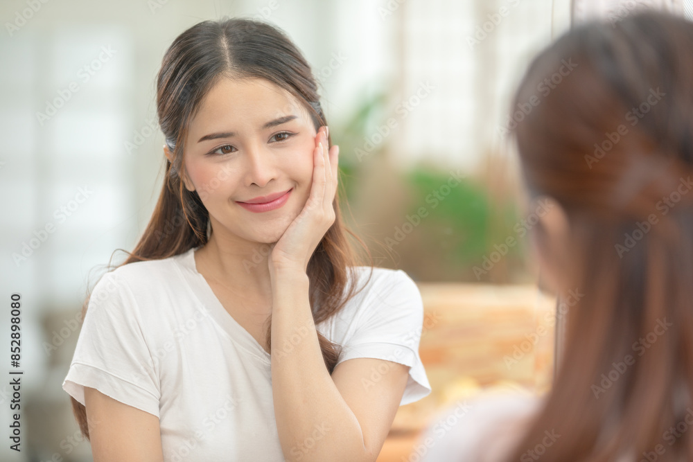Asian Woman Admiring Smooth Skin in Mirror During Skincare Routine Asian Woman Admiring Smooth Skin in Mirror During Skincare Routine