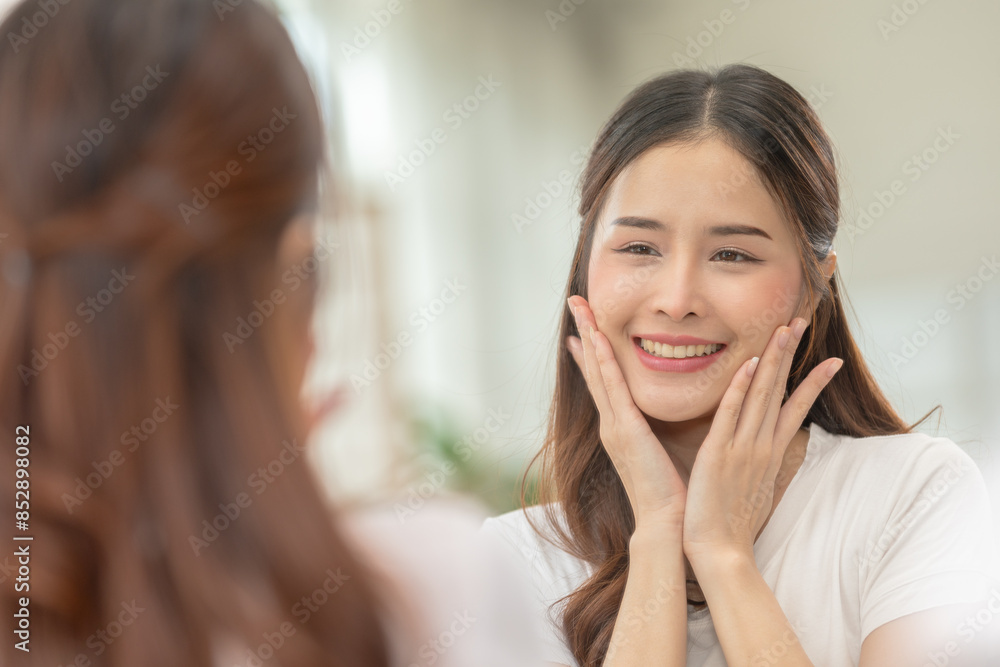 Asian Woman Admiring Smooth Skin in Mirror During Skincare Routine Asian Woman Admiring Smooth Skin in Mirror During Skincare Routine